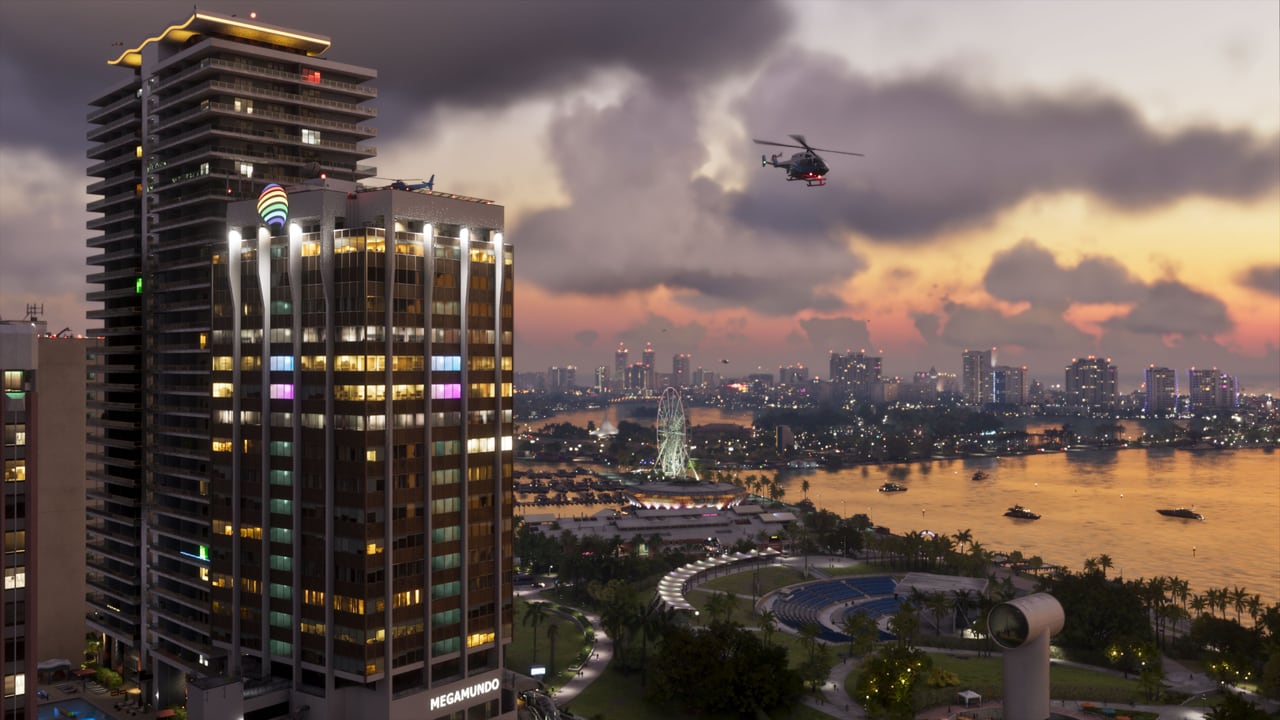 Official GTA VI screenshot of the Vice City skyline and bay at sunset, a helicopter over the water and a lit hotel tower in the foreground.